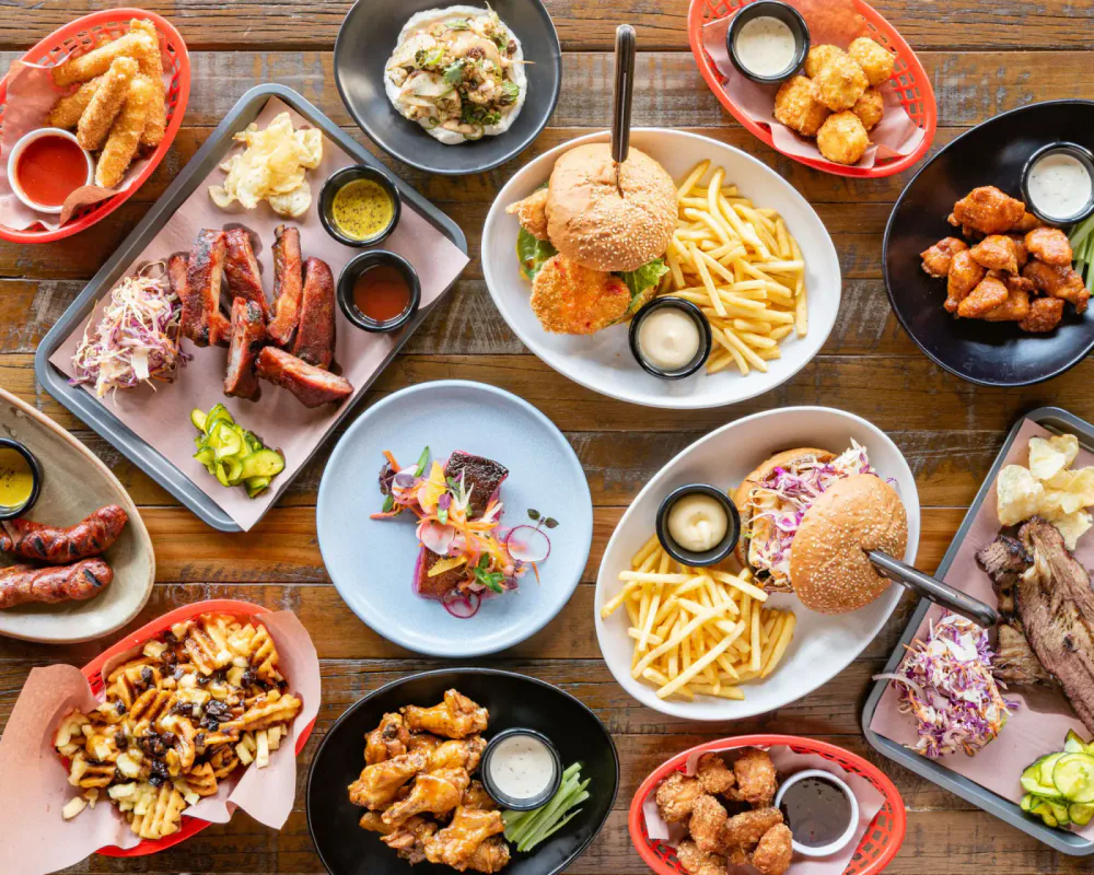 Burgers, fried chicken, ribs, fries and sides arranged across a restaurant table.
