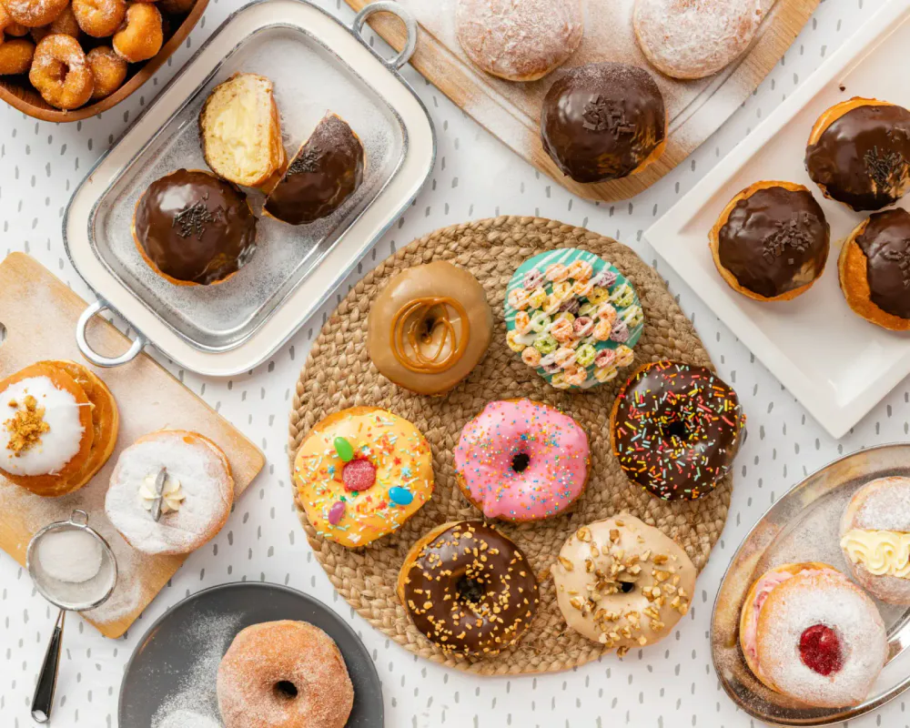 Assorted decorated donuts and sweet treats arranged on various plates and surfaces.