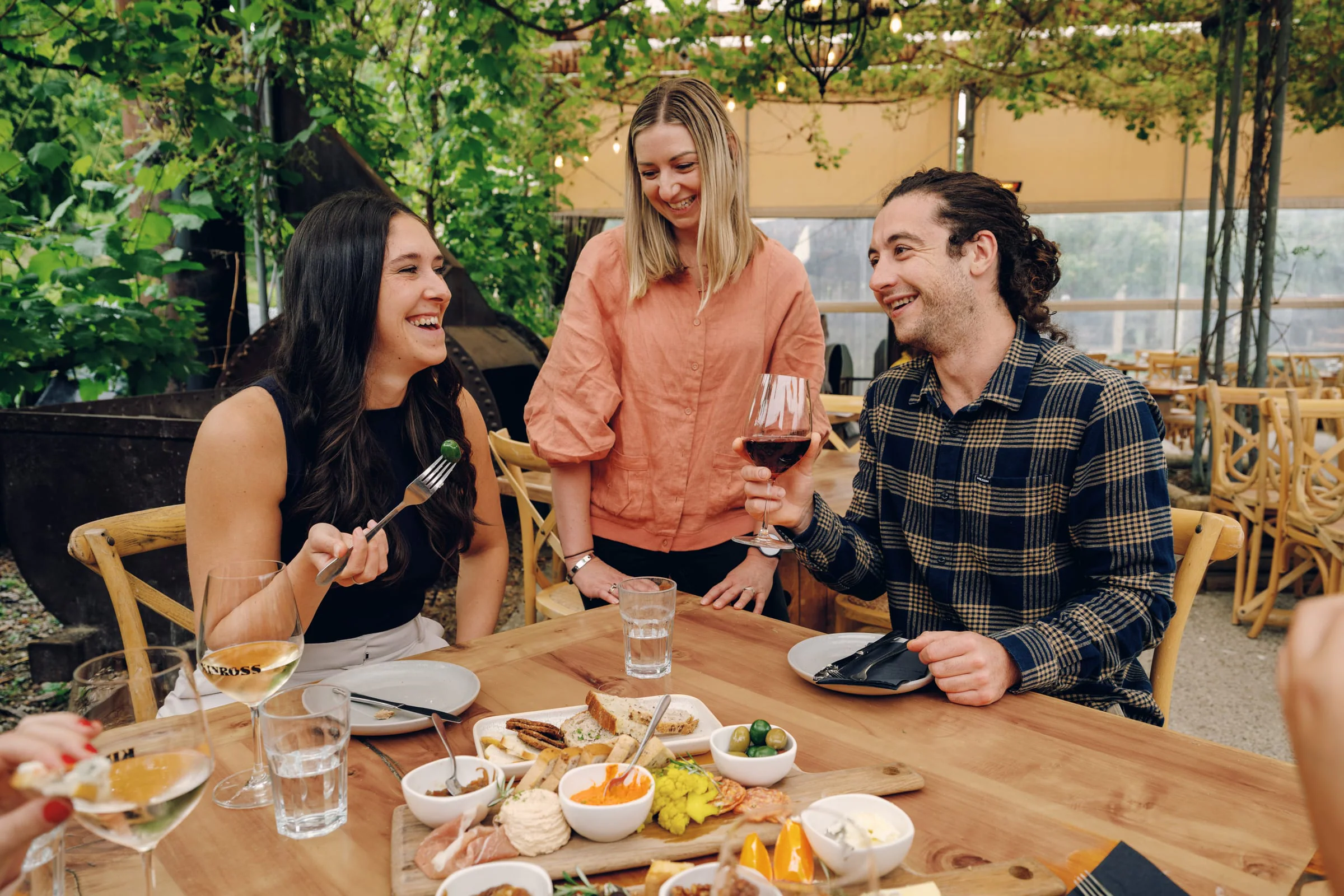 Restaurant guests sharing food and wine while a staff member serves their table