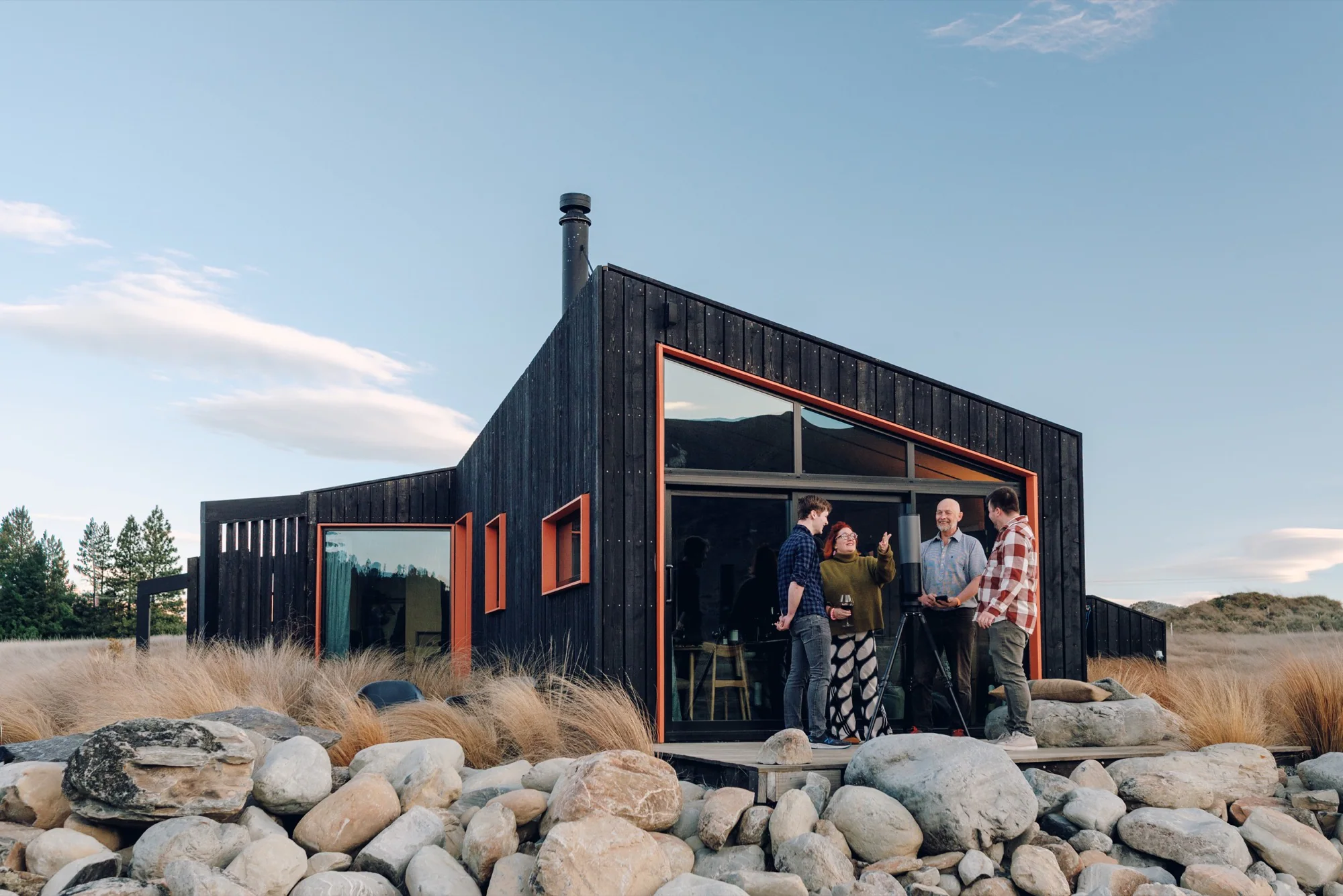Four guests talking outside Skylark Cabin in a rocky South Island landscape